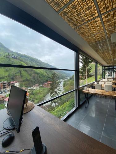 a room with a desk with a view of a river at Vadidekal Suite Hotel in Çamlıhemşin