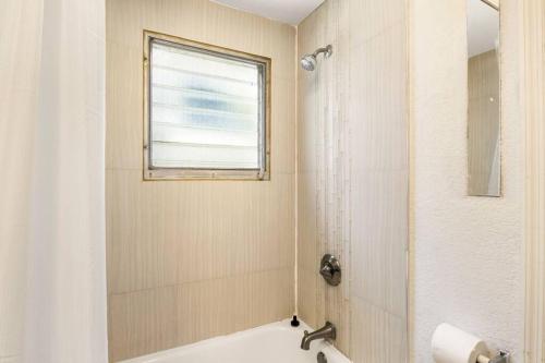 a bathroom with a shower and a tub and a window at Sunset Citrus Studio in St Petersburg