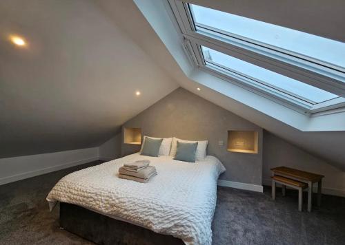 a bedroom with a large bed with a skylight at Romille Cottage in Skipton