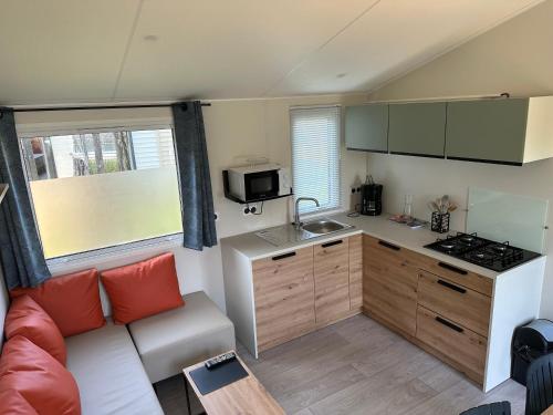 eine Küche mit einem Sofa und eine Küche mit einer Mikrowelle in der Unterkunft Camping La sablière in Saint-Jans-Cappel