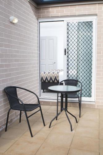 a patio with a table and two chairs and a window at Altitude Motel Apartments in Toowoomba