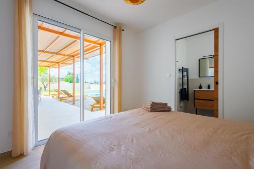 une chambre avec un lit et une porte coulissante en verre dans l'établissement L'Ostalada LEMH - Magnifique maison 8 personnes, à Cairanne