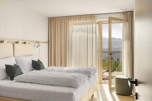a bedroom with a bed and a large window at Nikolausberg - Hof im Garten in Caldaro