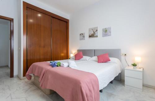 1 dormitorio con 2 camas con sábanas rosas y blancas en Acceso Sevilla Piscina Moderno Parking Gratis, en Bormujos