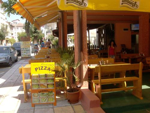 a restaurant with tables and chairs and a yellow umbrella at Guest House Nedelchevi in Primorsko