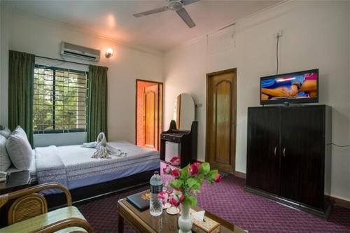 a bedroom with a bed and a tv on the wall at Excelsior Sylhet Hotel & Resort in Sylhet