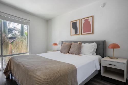 a white bedroom with a large bed and a window at Blueground Mid-Wilshire pool nr food shops LAX-1210 in Los Angeles