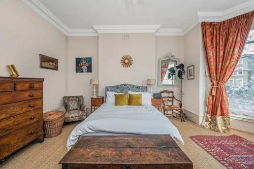 a bedroom with a bed and a dresser and a window at Pass the Keys Exquisite Flat - Ten minutes to Central London in London