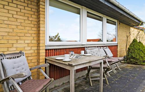 a wooden table and chairs on a patio at Cozy Home In Nørre Nebel With Wifi in Nørre Nebel