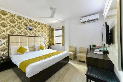 a hotel room with a large bed and a desk at Hotel First by Goyal Hoteliers in Agra