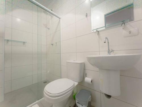 a white bathroom with a toilet and a sink at Charmoso Apto com Vaga Ar AM206 in Maringá