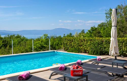 a swimming pool with two lounge chairs and an umbrella at Stunning Home In Malinska in Malinska