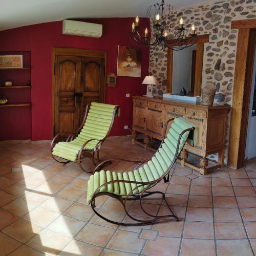 - deux chaises vertes dans une pièce avec un miroir dans l'établissement Le Petit Caboulot en pleine nature, à Vaumeilh