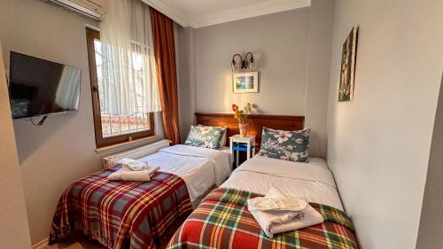 a room with two beds and a window at Cunda Nesos Pansiyon in Ayvalık