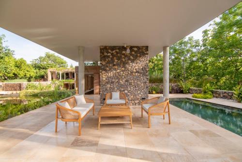 un patio con 2 sillas, una mesa y una piscina en The Sinaba Orchard's Pondhouse, en Buleleng