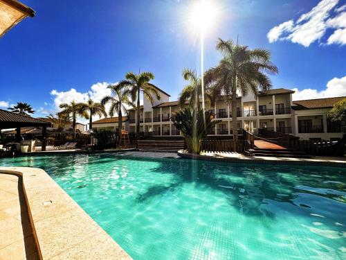 una gran piscina en un complejo con palmeras en Apartamento amplo de frente para o mar em Resort, en Entre Rios
