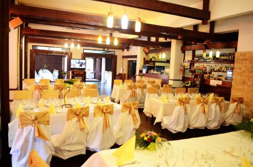 um salão de banquetes com mesas brancas e cadeiras com arcos em Pensiunea Valea Ursului em Bascov