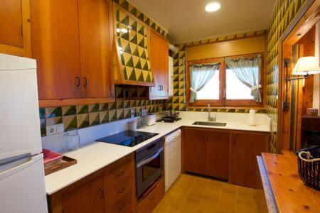 una cocina con armarios de madera y encimeras blancas en Apartamento con encanto Alp, en Alp