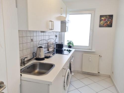 een witte keuken met een wastafel en een raam bij Apartment in Offenbach am Main in Offenbach