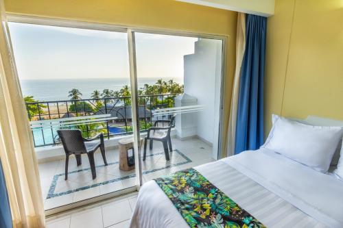 a bedroom with a bed and a balcony with the ocean at GHL Relax Hotel Costa Azul in Santa Marta