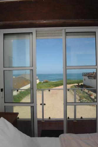 a bedroom with a view of the ocean seen through windows at Vivenda Sol E Mar in Baleal