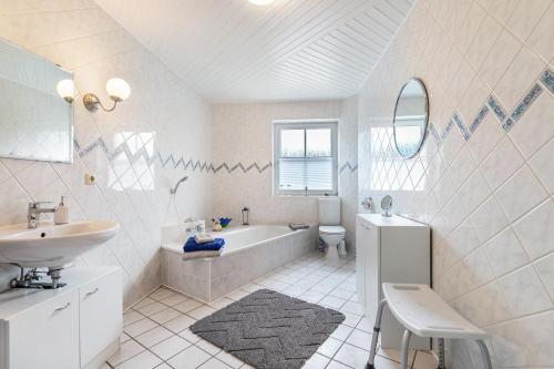 La salle de bains blanche est pourvue d'une baignoire et d'un lavabo. dans l'établissement Ferienwohnung Anke Volkmann, à Offenbüttel