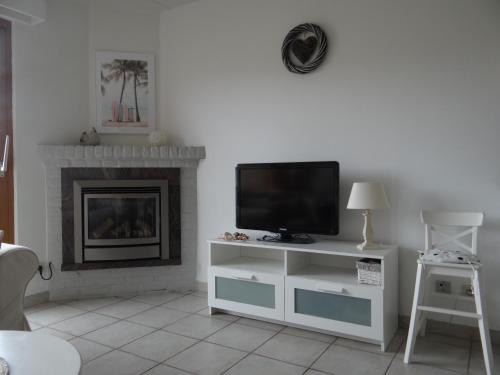 a living room with a tv and a fireplace at Golfbreker in De Haan