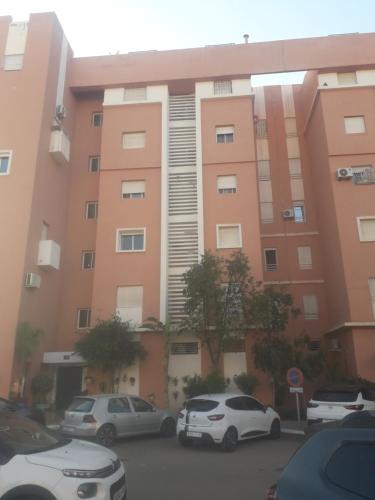 a pink building with cars parked in a parking lot at ديار الاطلس بني ملال المغرب in Beni Mellal