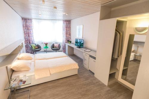 een slaapkamer met een bed, een bureau en een televisie bij Hotel Cronberger Hof in Ladenburg