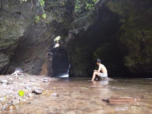un homme assis dans l'eau devant une grotte dans l'établissement Goa Walet Cottage, à Praya