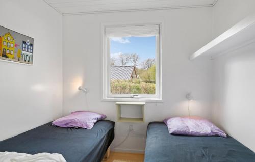 Cozy Home In Haderslev With Kitchen في هادرسليف: سريرين في غرفة مع نافذة