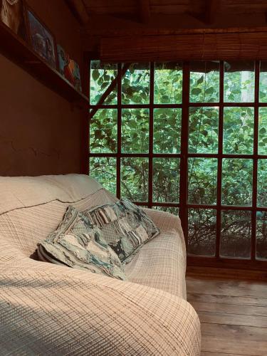 a bed with a pillow in a room with windows at CABAÑA en Eco Posada Tierra Fértil in Santa Ana