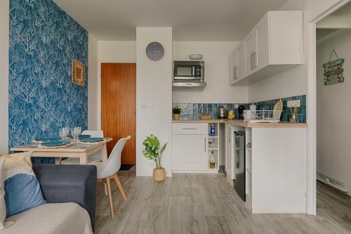 a kitchen and a living room with a table at Le Coquillage Bleu, charmant 2 pièces, proche plages et commerces in Cabourg