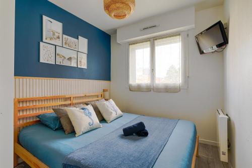 Un dormitorio con una cama con una maleta. en Le Coquillage Bleu, charmant 2 pièces, proche plages et commerces, en Cabourg