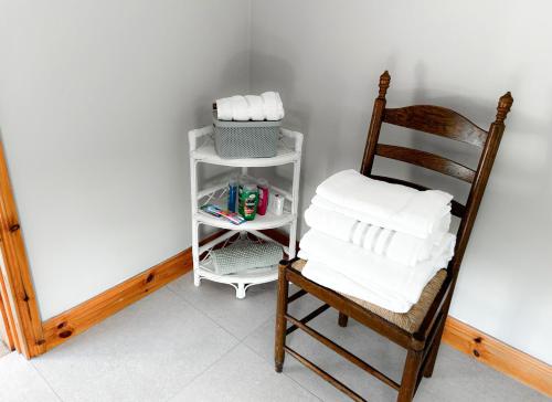 a room with a chair and a shelf with towels at Lisheenbawn Farmhouse Farranfore in Farranfore