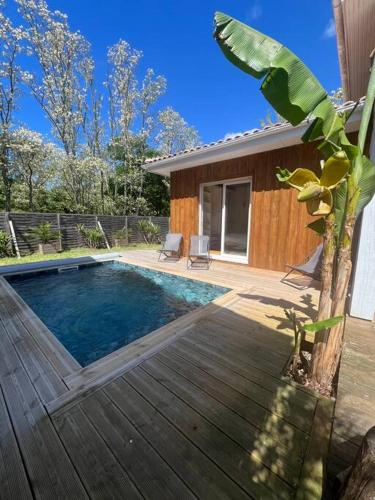 - une piscine avec une terrasse en bois à côté d'une maison dans l'établissement Villa avec piscine proche du lac, à La Teste-de-Buch
