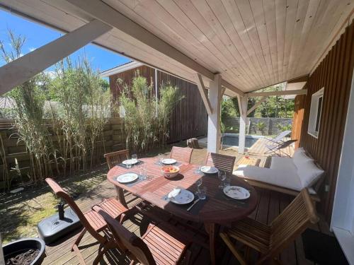 Une table et des chaises en bois sont disponibles sur la terrasse. dans l'établissement Villa avec piscine proche du lac, à La Teste-de-Buch