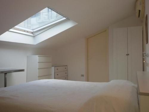 um quarto com uma grande cama branca e uma clarabóia em Mansarda luminosissima em Pesaro