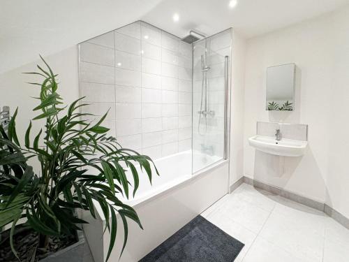 uma casa de banho branca com um chuveiro, um lavatório e uma planta em Long Term Business Stays - Relocating Families em York