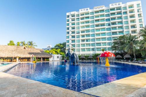 a swimming pool in front of a large building at GHL Relax Hotel Costa Azul in Santa Marta