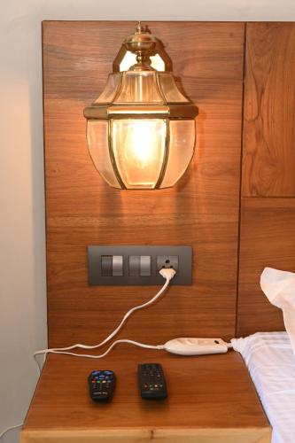a light on a bed with two remote controls on a table at Kabana de Nature in Rājgarh