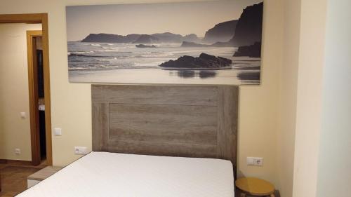 a bed in a room with a picture on the wall at Fondás in Foz