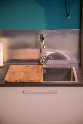 a kitchen sink with a wooden cutting board next to it at RHS - Casa Consani in Ventimiglia