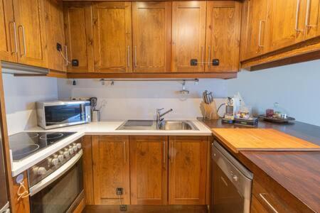 La cuisine est équipée de placards en bois, d'un évier et d'un four micro-ondes. dans l'établissement Apartament les Carrerades, à Estavar