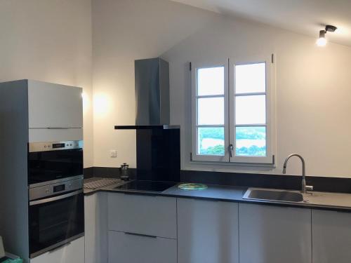 a kitchen with white cabinets and a black appliances at Newly converted barn, magnificent vues, garden and pool in Lauzerte