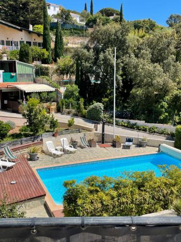 vista su una piscina con sedie e alberi di Résidence Le Golfe Bleu a Le Rayol-Canadel-sur-Mer