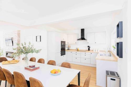 a white kitchen with a white table and chairs at Luxury SeaWay sleeps 12, playroom/xbox in Barton on Sea