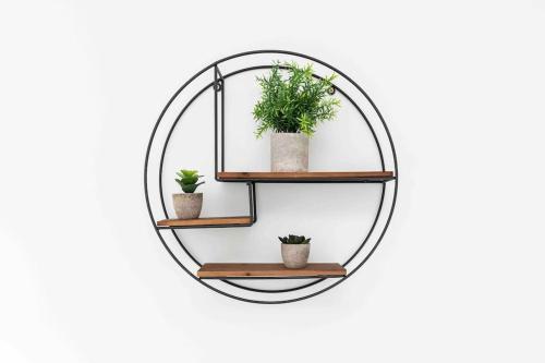 a round mirror with three potted plants on a wall at Luxury SeaWay sleeps 12, playroom/xbox in Barton on Sea