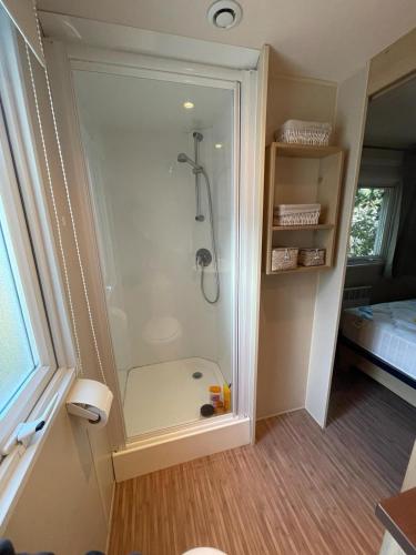 une salle de bain avec une douche avec une porte vitrée dans l'établissement Maison mobilhome sans vis à vis au calme et en hauteur, à Lège-Cap-Ferret