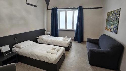 een kamer met 2 bedden en een bank en een stoel bij Residenza Novi in Novi Ligure